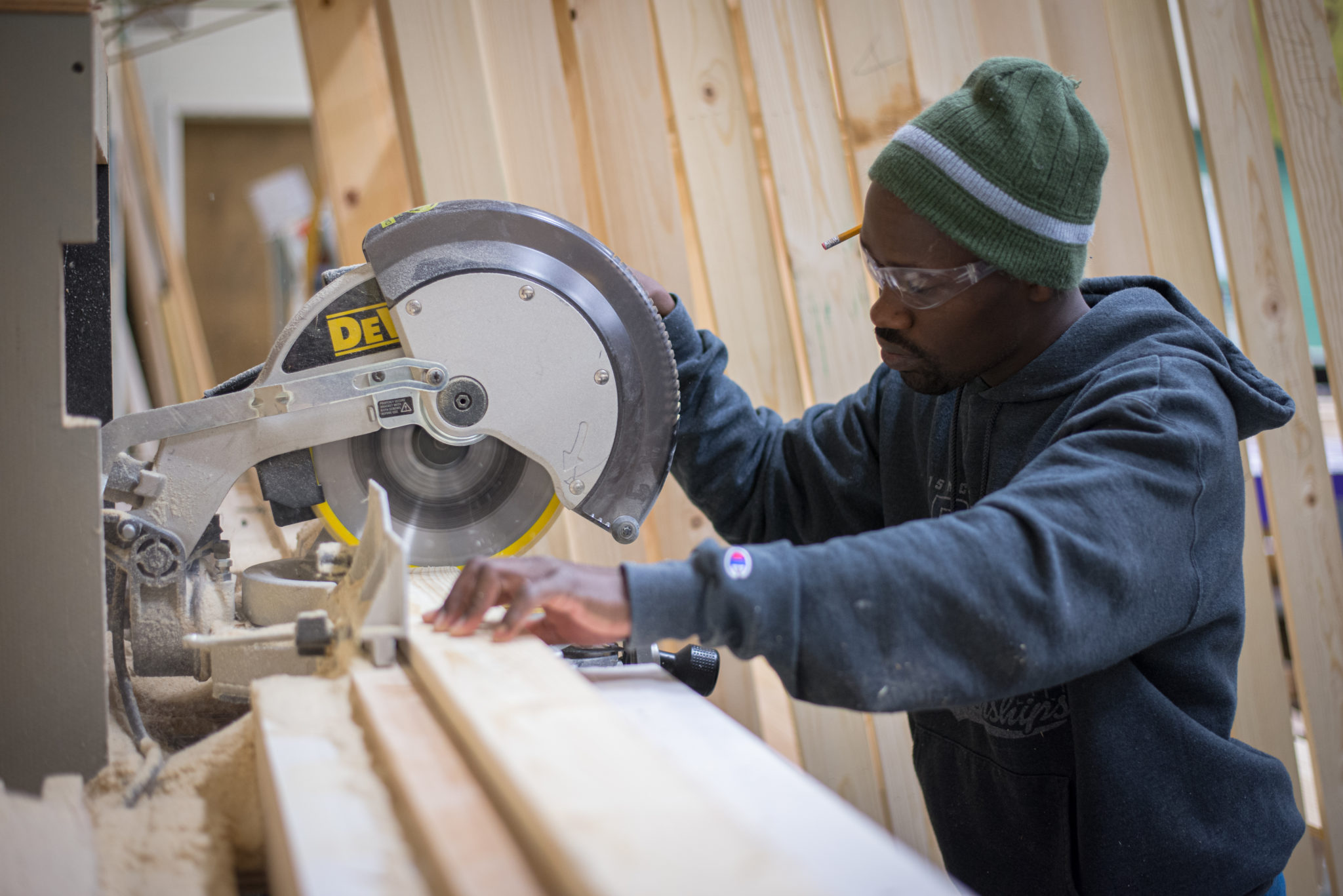 Student operating a vertical circular saw on a plank of wood