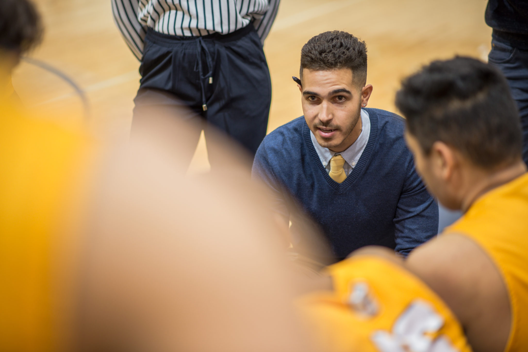 A coach in a huddle with a team of students on a gym floor