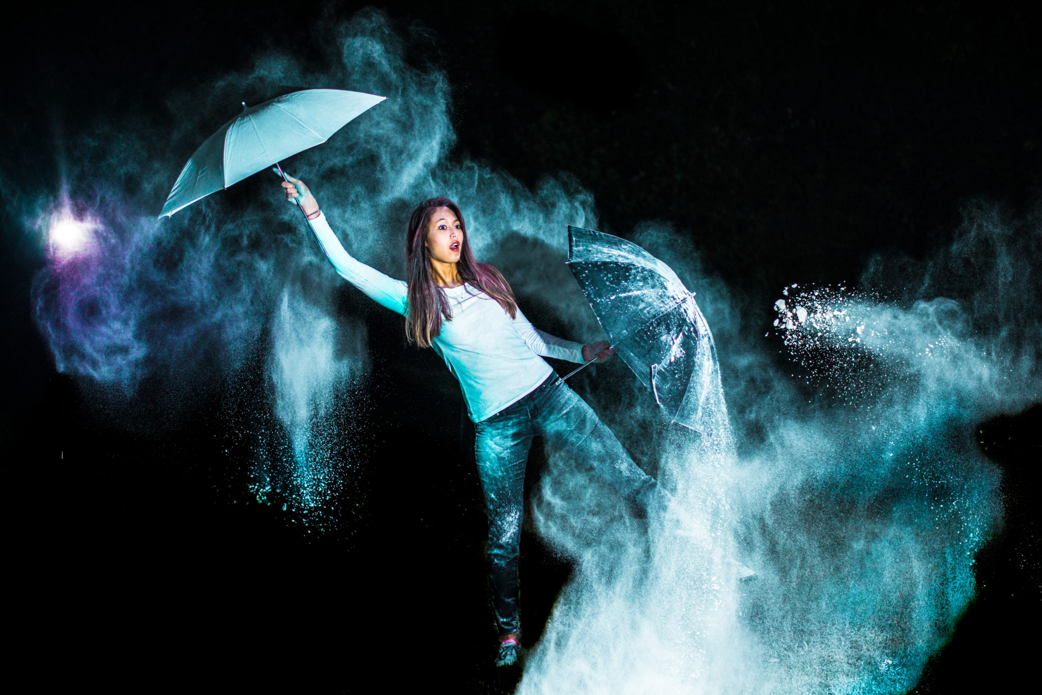 Student holding two umbrellas in colorful clouds on a dark background