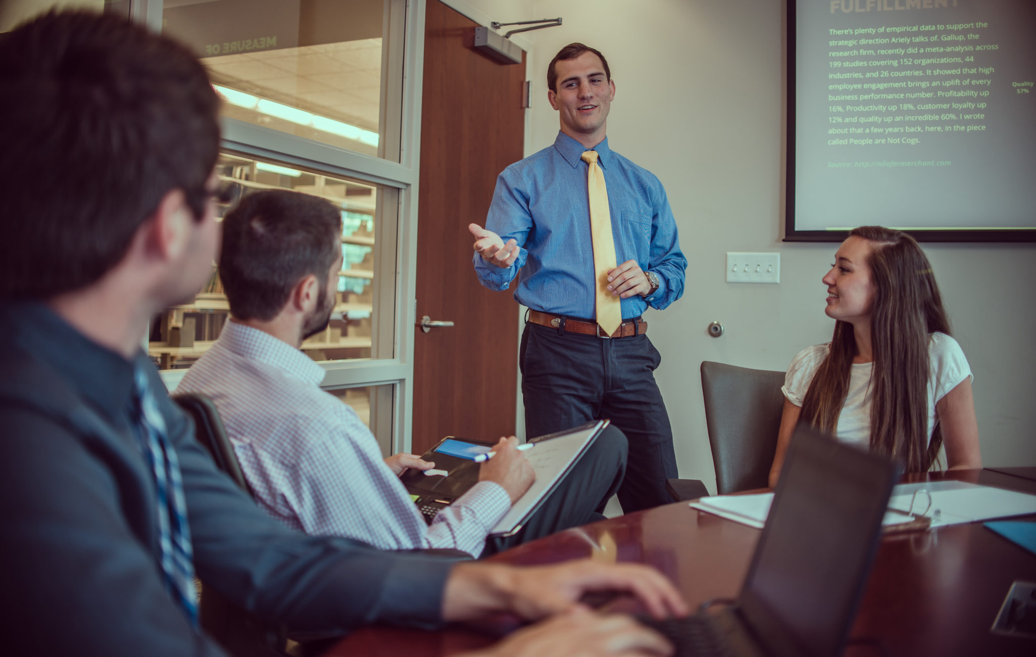 4 people in a conference room, with 1 of them standing and presenting to the others