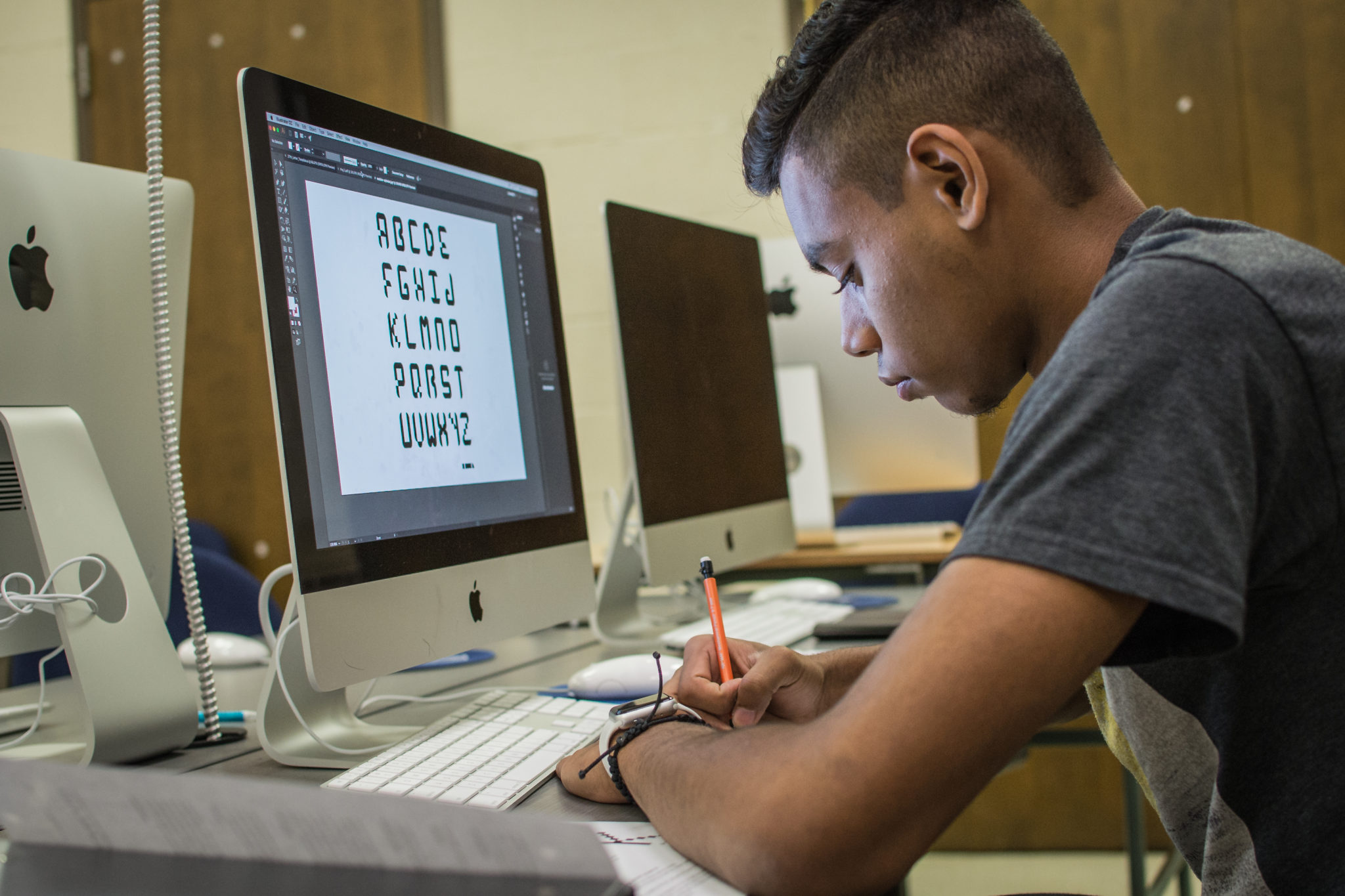 Student writing at a desk with a computer