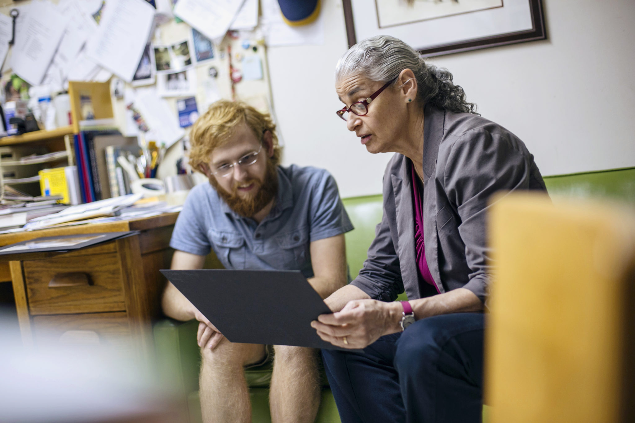 Student and professor seated on couch discussing artwork