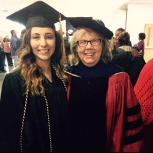 Photo of Mollie Moree and another person, both in graduation gowns, at a graduation event