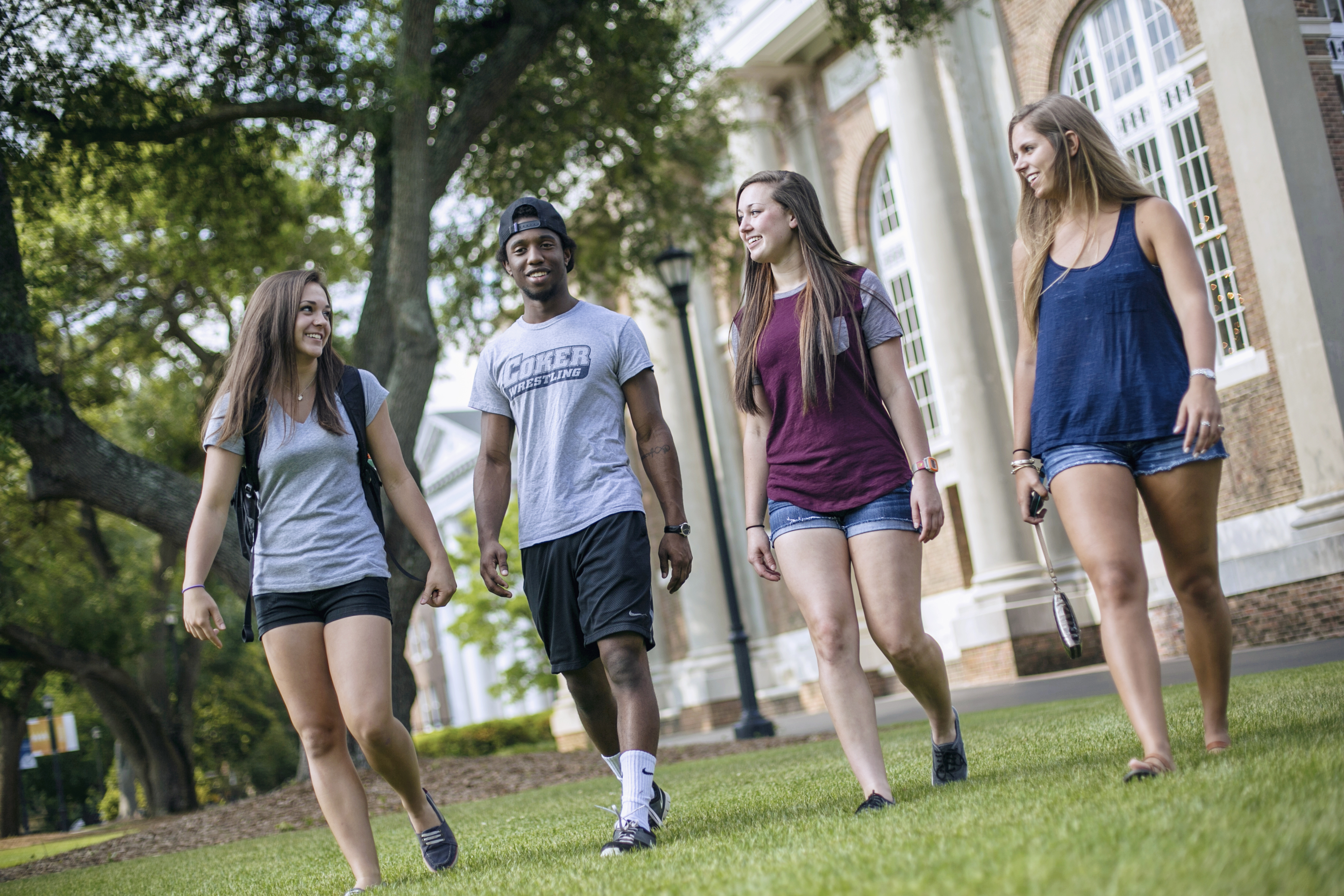 Four students walk across campus