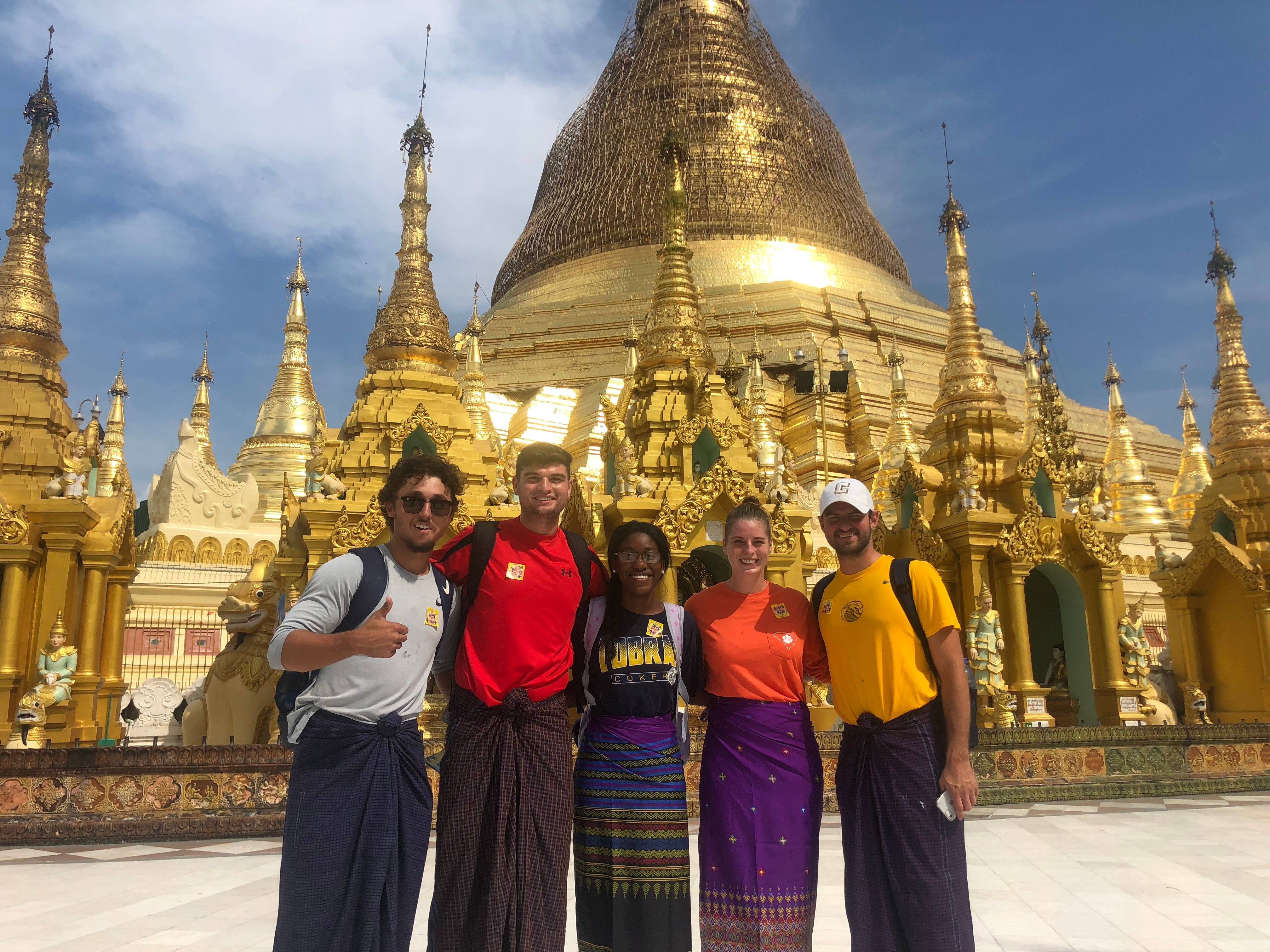 A group of five students pose in front of a temple in Myanmar