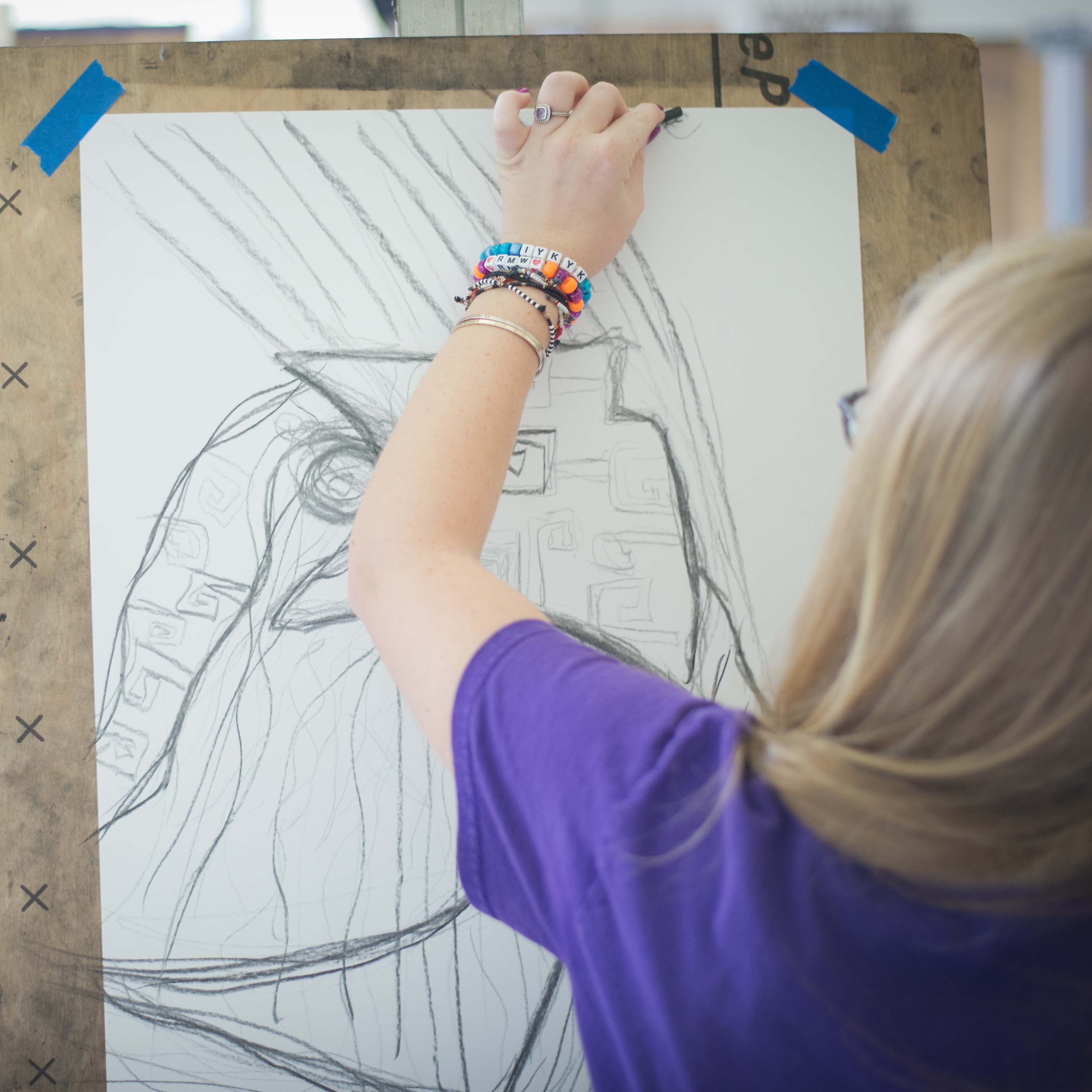 A student sketches on paper taped to an easel