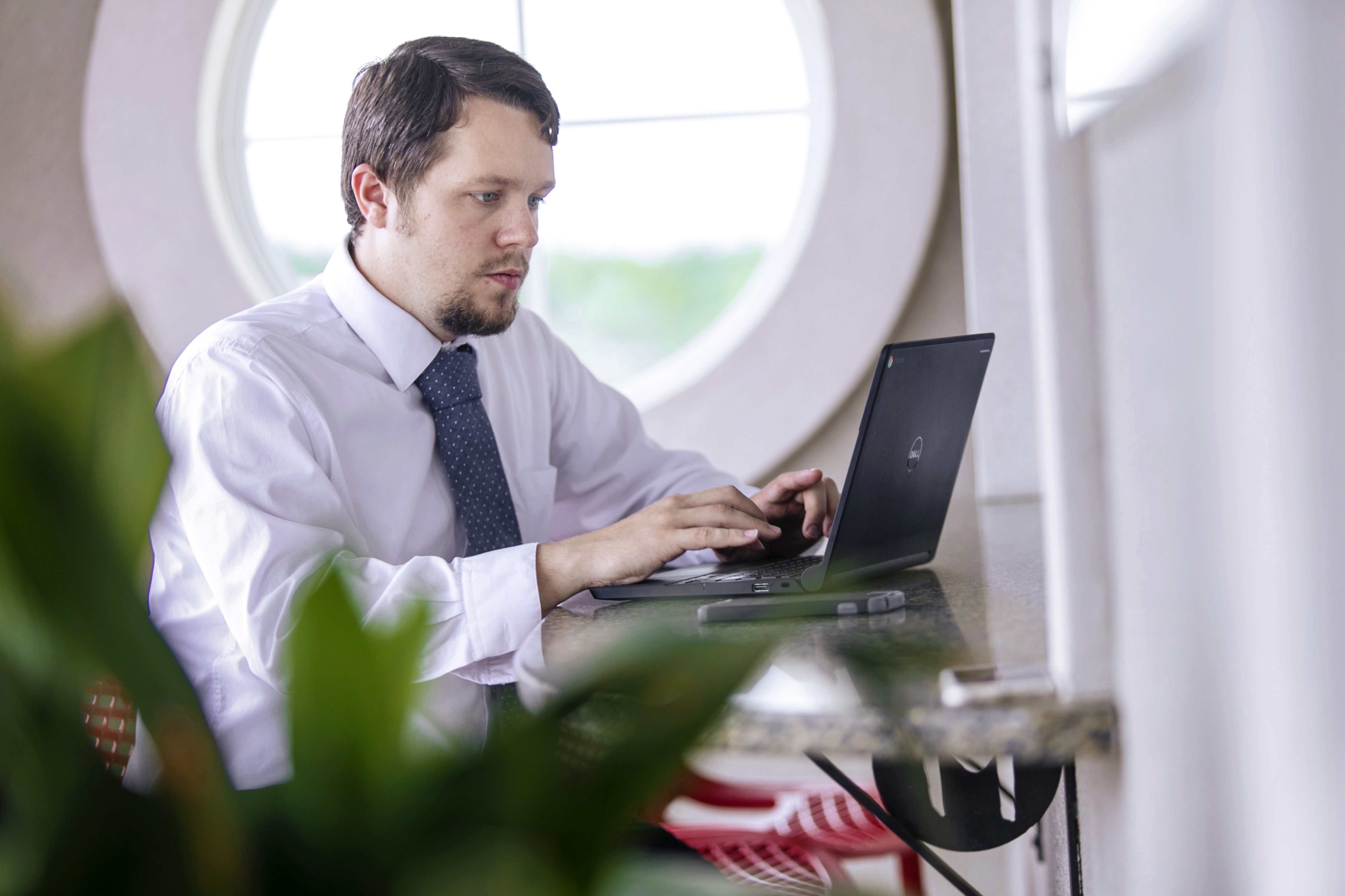 A young man in a suit and tie types at a laptop