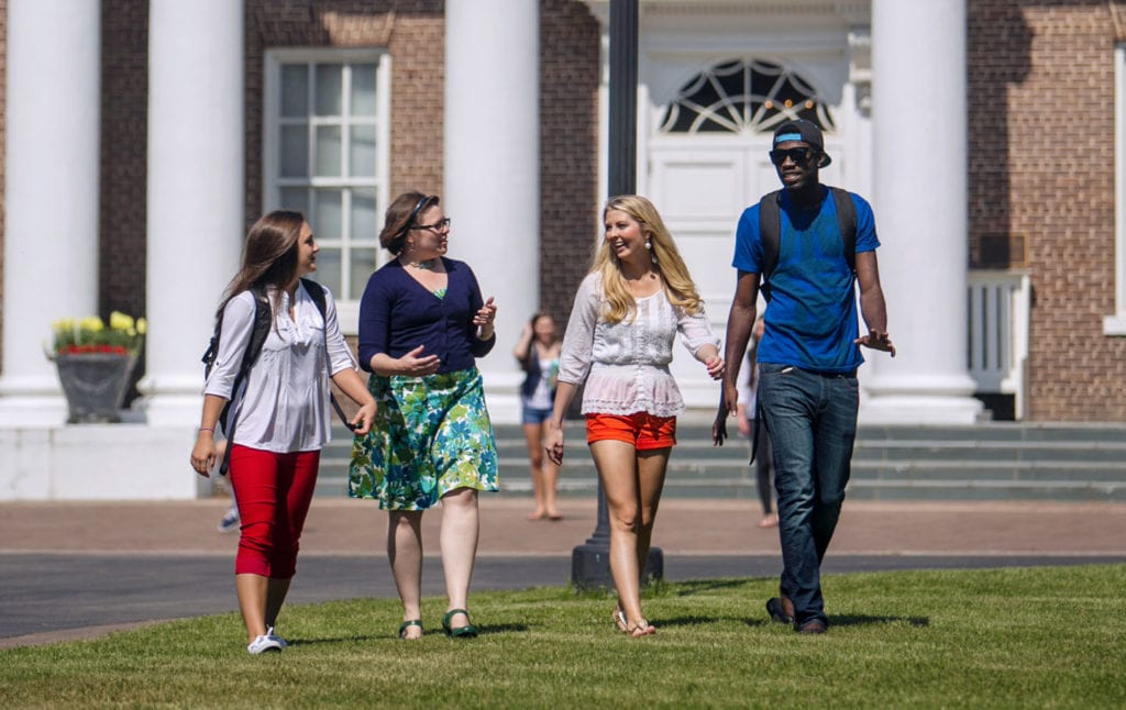 4 people walking on the lawn in front of Davidson Hall at Coker University