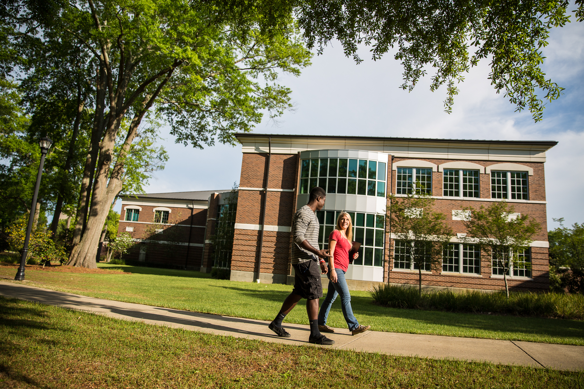 Two students walking along a path near the Library-Information Technology Center at Coker