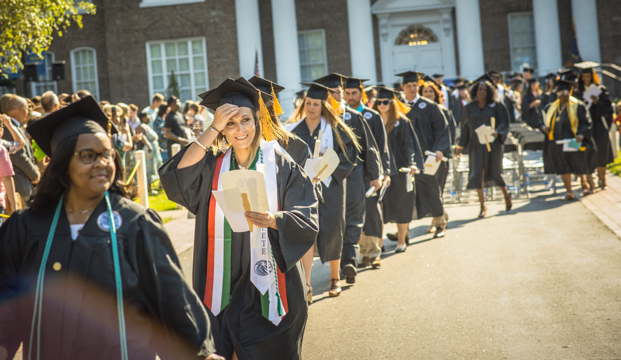 A row of students walking away in a line from their seats at their graduation during the recessional.