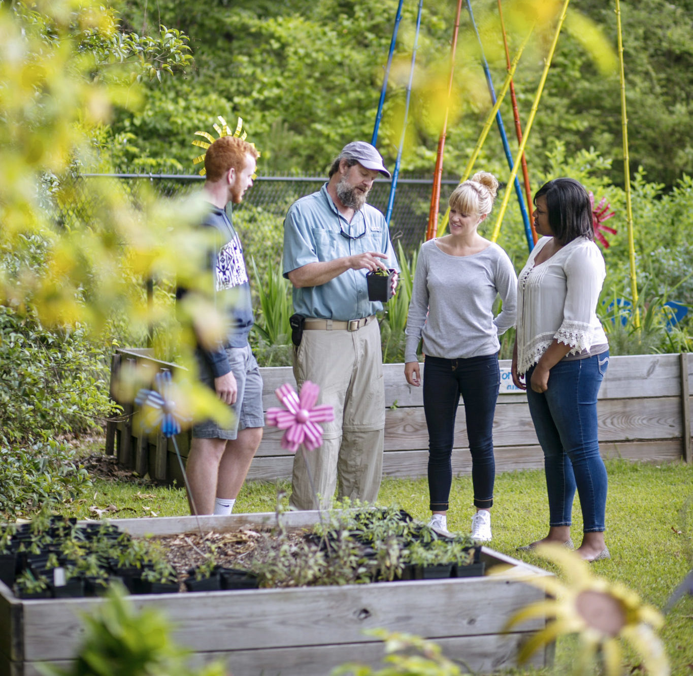 3 students and a professor examining a plant at Kalmia Gardens
