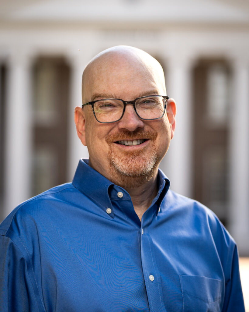 Charlie Poag smiles for a headshot in front of Davidson Hall