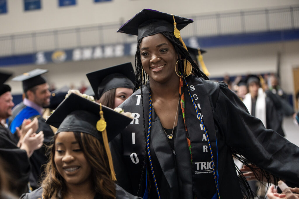 A graduate student stands up to receive her diploma.