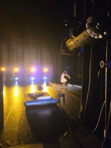 A male dancer performs on stage next to an air mattress.